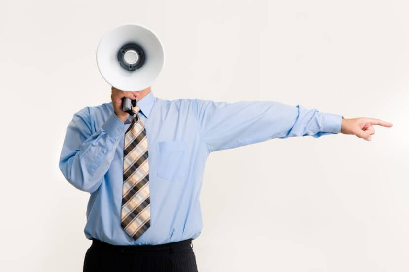 Man holding a megaphone and pointing, representing the German imperative with examples like 'Hör zu!' (Listen!) and 'Geh!' (Go!).