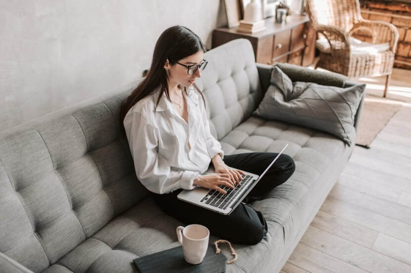 A person sitting on a couch studying German genitive verbs on a laptop for advanced grammar learning.