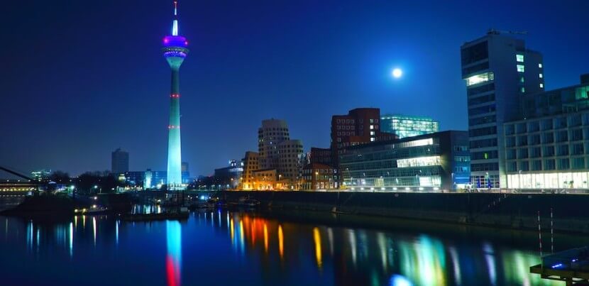 Nighttime view of Düsseldorf cityscape with the Rhine Tower illuminated, representing the contrast in German concessive clauses.