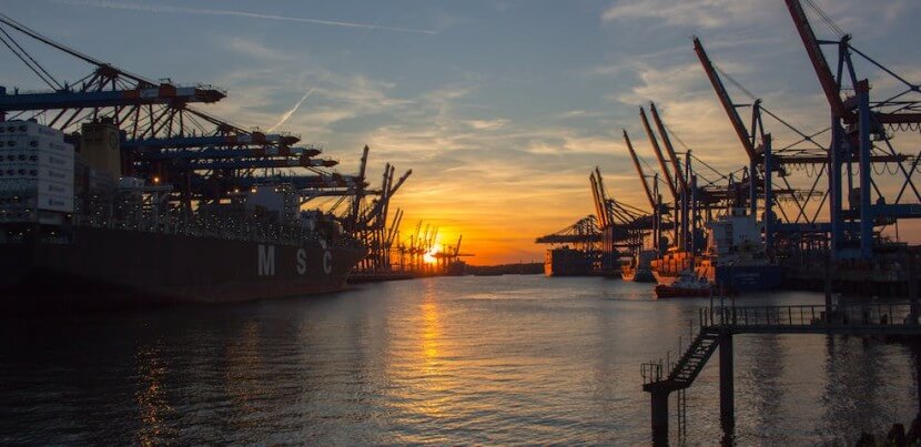 Hamburg port at sunset with cranes and ships, demonstrating an industrial setting to learn German adjectives for beginners.