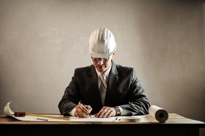 Architect in a hard hat working on a draft, illustrating German professions vocabulary like der Architekt (architect).