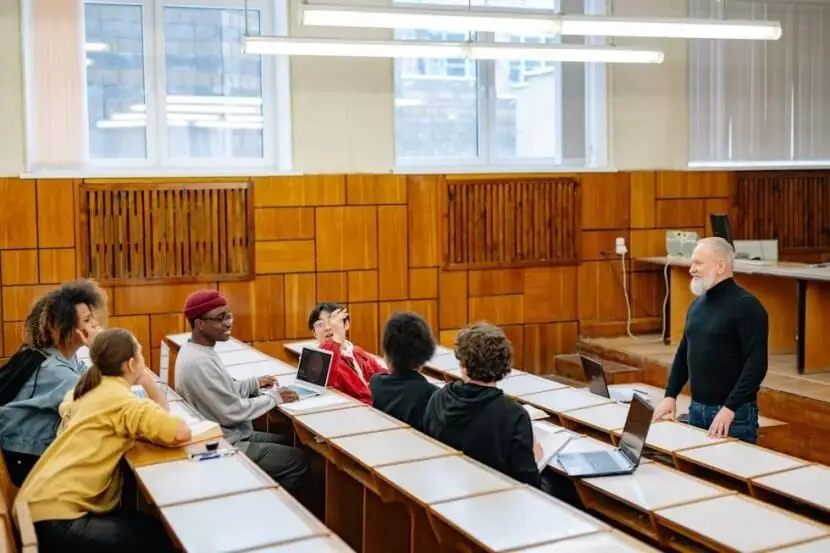 A teacher explaining the German verb 'sein' and its conjugation to a group of students in a classroom setting.