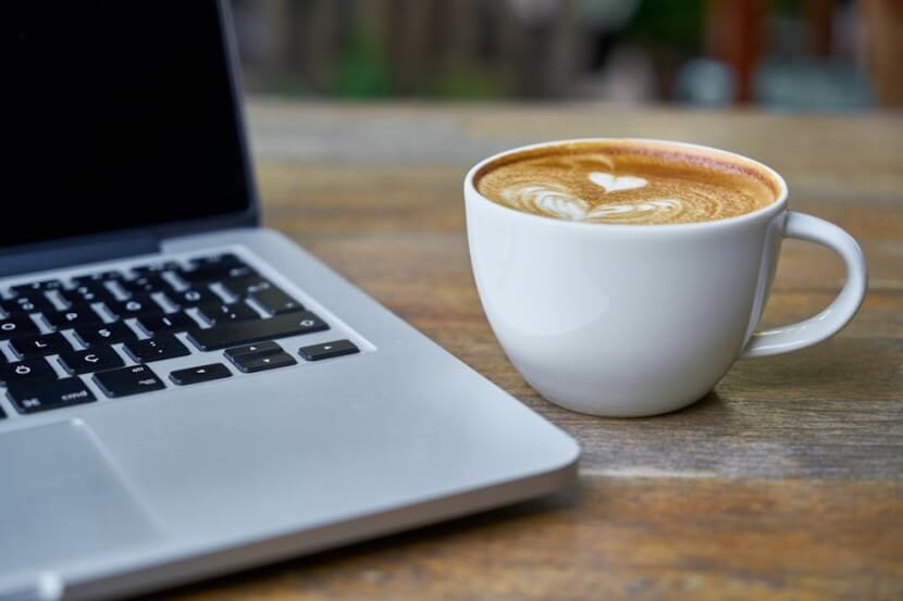 A cup of coffee next to a laptop, representing German daily routine vocabulary.