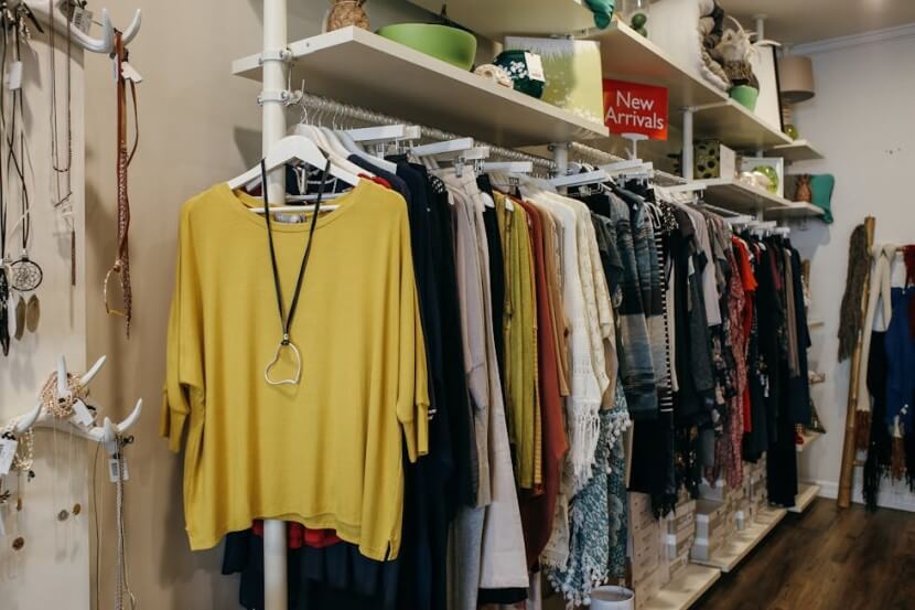 Boutique with racks of colorful clothes, representing German clothing vocabulary like der Pullover (sweater) and die Hose (pants).