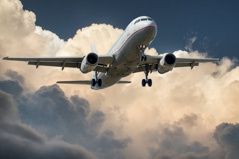 Airplane flying through clouds, representing German travel vocabulary like der Flughafen (airport).