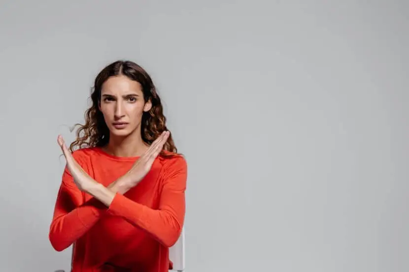 Woman in red shirt making an X gesture to symbolize German negation with 'Nicht' and 'Kein.'