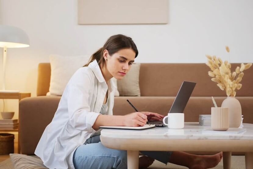 Young woman studying with a laptop and taking notes for German grammar quizzes overview.