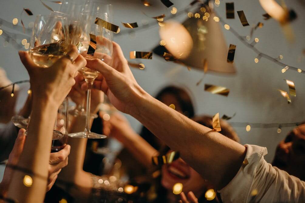 People celebrating with champagne and confetti at a festive holiday party.