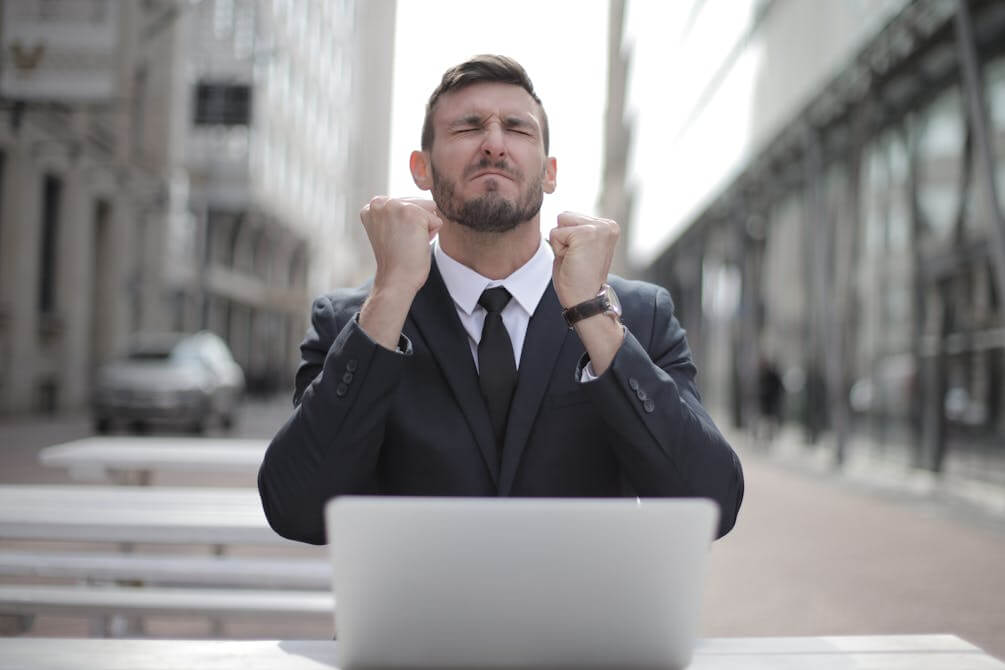 Man in a suit celebrating after receiving a job offer, representing success in a German job application process.