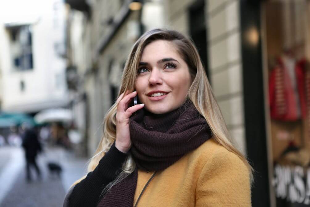 Young woman in a city talking on the phone, illustrating casual phone conversations in German.