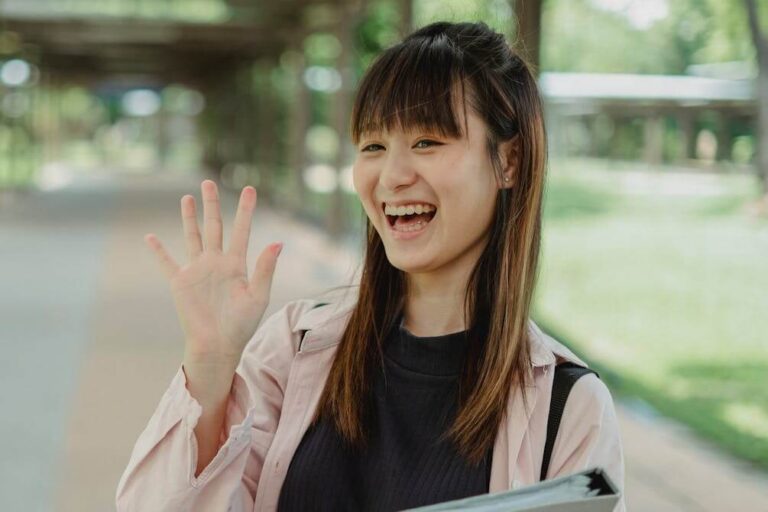 Woman smiling and waving as an example of body language used in the German body language quiz