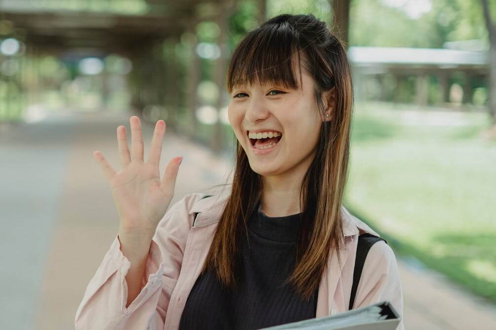 Woman smiling and waving as an example of body language used in the German body language quiz