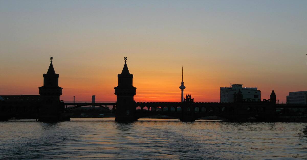 A silhouette of the Berlin skyline at sunset featuring the Oberbaum Bridge and the TV Tower, illustrating the German masculine noun der Arbeitgeber.